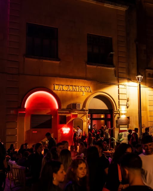 L'insegna al neon de La Cambusa di sera, con il dehors pieno